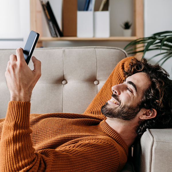 Guy smiling looking at phone on the couch