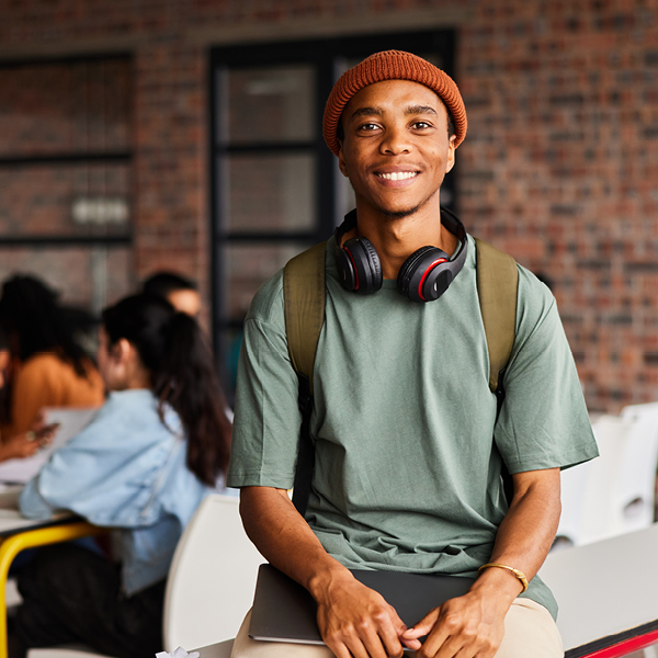 Smiling student sitting on desk with book and headphones